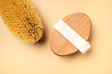 Body massage brush with natural bristles on beige background. Spa treatments, body care, anti-cellulite massage at home. Minimalistic concept of eco-friendly cosmetic accessories