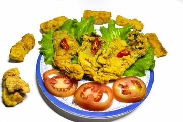 Photo of crispy fried mushroom food served on a plate and a bowl of sauce decorated with tomatoes and chilies on the side, on a white background. isolated