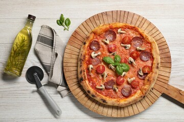 Delicious pizza with tomatoes, salami, mushrooms and basil on wooden table, flat lay