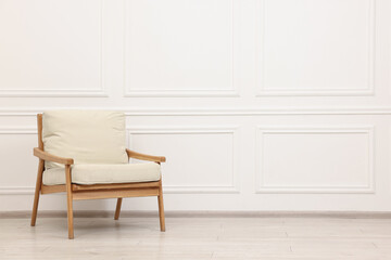 Comfortable soft armchair near white wall, space for text