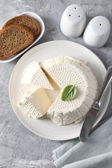 Tasty ricotta (cream cheese), bread and knife on grey table, flat lay