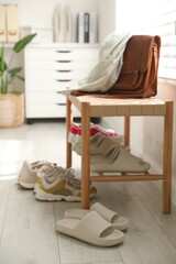 Many pairs of slippers and other shoes in entryway at home