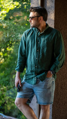 A charismatic middle-aged man, slightly overweight, posing in front of a scenic window with the evening sun shining through