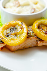 A plate of food with a piece of salmon and a couple of yellow slices of lemon