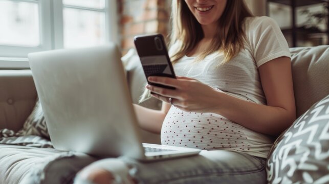 Relaxed pregnant woman on sofa with phone and laptop in living room reading email or text. Internet, video call, or social media, smiling pregnant woman on couch.