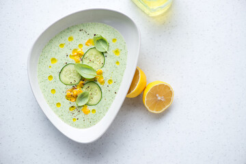 Cucumber and sweet corn soup on a white stone background, horizontal shot with space, above view