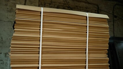 A pile of corrugated cardboard. Bandaged cardboard for packaging, lying in a warehouse. Sheets of cardboard for packaging, laid in a row.