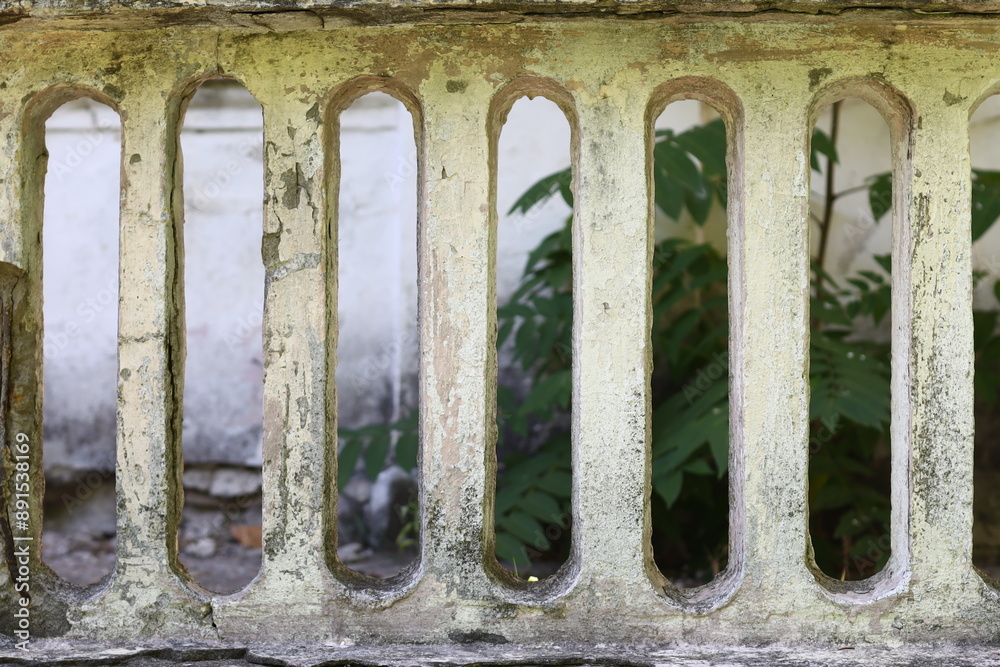 Poster a close-up view of a metal grate with a small plant growing in the background, suitable for use in i