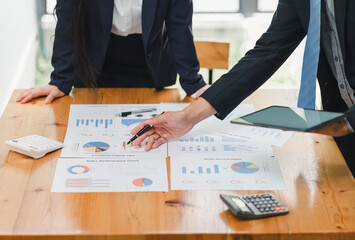 Two professionals analyzing business data on dashboard screen and discussing financial graphs and charts in a modern office.