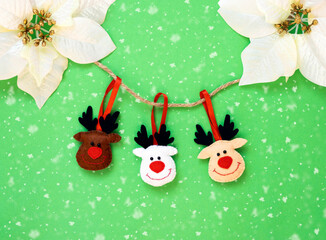 Toy Deers hanging on a rope isolated on the green background with copy space. The atmosphere of Christmas and New Year. Christmas banner, mock-up