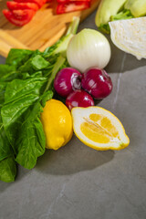 A variety of vegetables are placed on the table near a cutting board