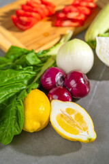 There are various vegetables placed on the table next to a cutting board