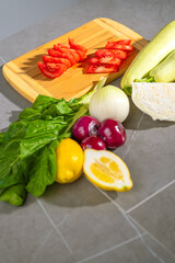 Cutting board with vegetables tomatoes, onions, lemons, and more