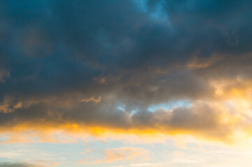 Blue sky background - picturesque colorful clouds lit by sunlight, sunset evening sky view in warm tones