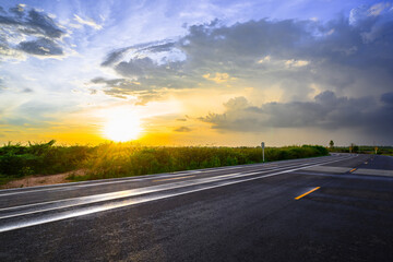 Fototapeta premium Wet asphalt road after rain in countryside at sunset, with a beautiful sky, and rain clouds