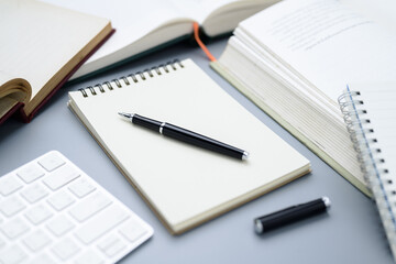 Closeup a pen on the empty notebook with many books around on the table, create a new content,...