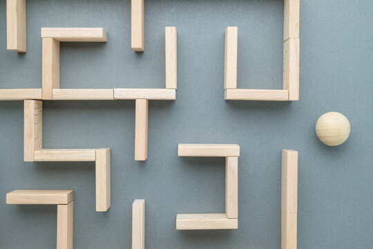 Wood ball and a labyrinth game built by wood blocks, confused situation, complicated problem, find a right direction to go through