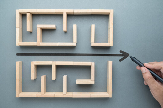 Hand draw a shorten straight line to go through the complication of a maze game, built by wood blocks, shorten process, simplify, and communication concept