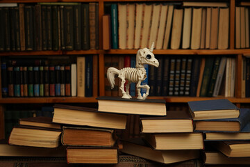 Skeleton of a unicorn against the background of bookshelves in a library. © Oksava