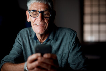 Senior man, night and phone in office for texting with communication, networking and reading email. Elderly employee, mobile connection and typing with working overtime, web news and chat app in dark