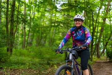 Cycling training in city. Young joyful woman in white helmet and colorful blouse and black shorts riding bike on bike path in city. Playing sports outdoors in spring. Healthy lifestyle
