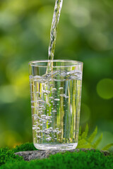 water pouring into glass on stone with moss