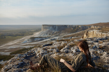 Woman contemplating the vast beauty of nature solitude and peace on the cliff's edge overlooking valley and mountains
