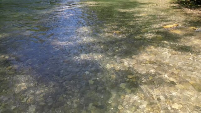 Aerial Drohnenflug r&uuml;ckw&auml;rts in niedriger H&ouml;he &uuml;ber eine Stromschnelle in einem Fluss mit kristallklarem Wasser in den Alpen, UHD