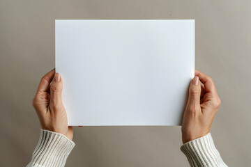 Obraz premium Female hands holding a blank white paper poster flyer on minimalistic background