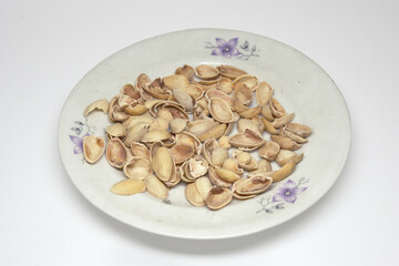 pistachio shells in white porcelain plate. on white background, with clipping path