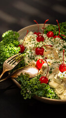 A tasty, traditional apple salad with cherries and arugula, served in a plate with a golden fork and spoon.