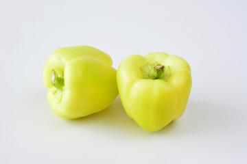two green peppers are on a white surface