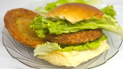 Simple Hamburger recipe with bun, fried ham and fresh lettuce on a plate isolated on white background. Close up view