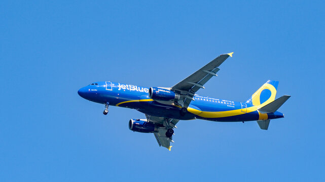 Alexandria, Virginia, USA - 1 May 2024: Airbus A320 jet (registration N775JB) operated by JetBlue in flight against a deep blue sky. The aircraft has a colour scheme to commemorate veterans.