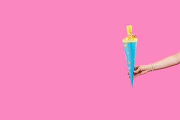 School cones in child hands on light pink background