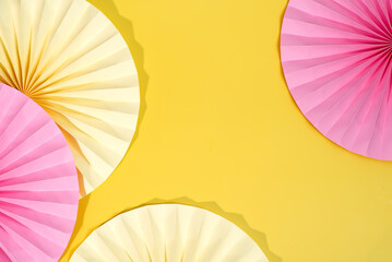 A variety of paper fans are displayed against a vibrant yellow background