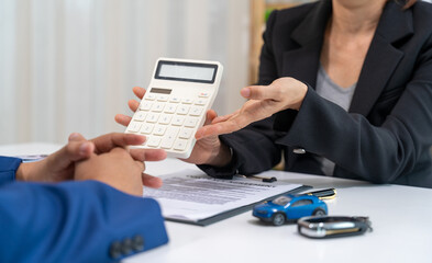 Asian businesswoman and salesperson discuss car sales, insurance and finance too.