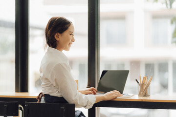 Young Asian woman sits at home and checks laptop computer orders from boxes of various sizes. Ideas for starting a business