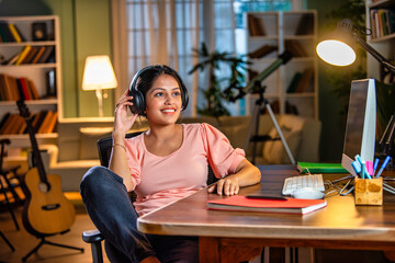 Indian asian  young student or businesswoman using laptop with coffee, books, smartphone, headphone