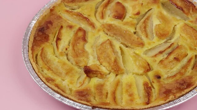 tarte normande, en gros plan, sur un fond rose