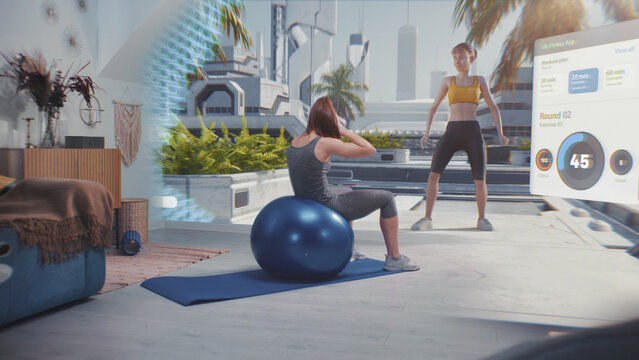 Sportswoman in AR headset exercises with fitball. VR screen shows virtual trainer, interface of fitness app with workout plan and image of futuristic city. Home gym with AI and metaverse technologies.