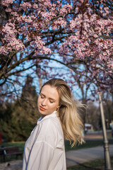 Woman with cherry flowers surrounded by blossoming trees copy space. Beauty and seasonal change and spring bloom season concept.