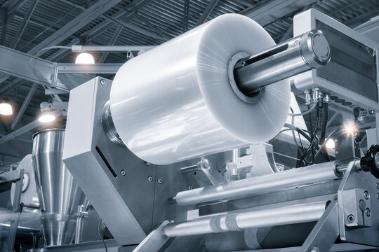 Automatic polyethylene plastic bag production machine with lighting effect. Close-up of the roller of the plastic bag production machine in the light blue scene. product packaging concept