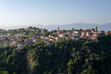 Fototapeta premium A picturesque view of Sighnaghi, a town in Georgia, bathed in the golden light of sunset. The town's charming architecture, nestled among verdant hills, creates a serene and breathtaking scene.