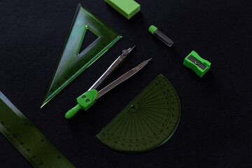 set of green geometry tools: rulers, compasses, eraser and sharpener lie on a black background. Mathematics and lesson at school
