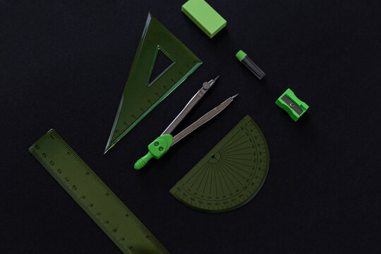 geometry set with rulers, compass, eraser, sharpener and graphite rods on black background
