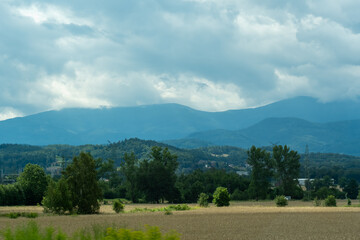 Mountainous landscape overlooking a wheat field and mountains in a misty haze on a sunny summer day. High quality photo