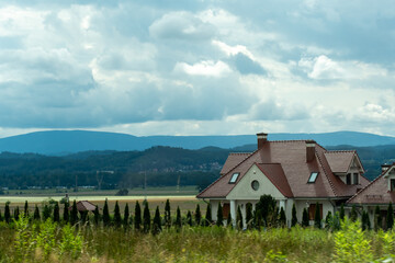 Beautiful one-story house in a field with a backdrop of mountains and beautiful nature. Concept of country life, privacy, silence and solitude. High quality photo © Maryia