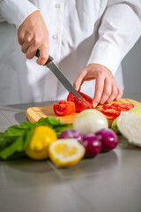 In the kitchen a chef is cutting tomatoes on a wooden cutting board