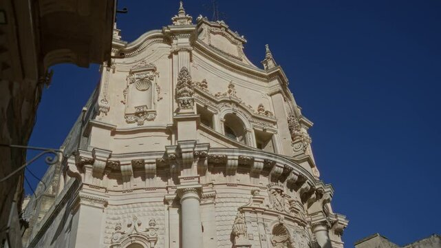 Detail of a stunning baroque building facade in the town of lecce, puglia, italy, showcasing intricate architectural elements under a clear blue sky.
